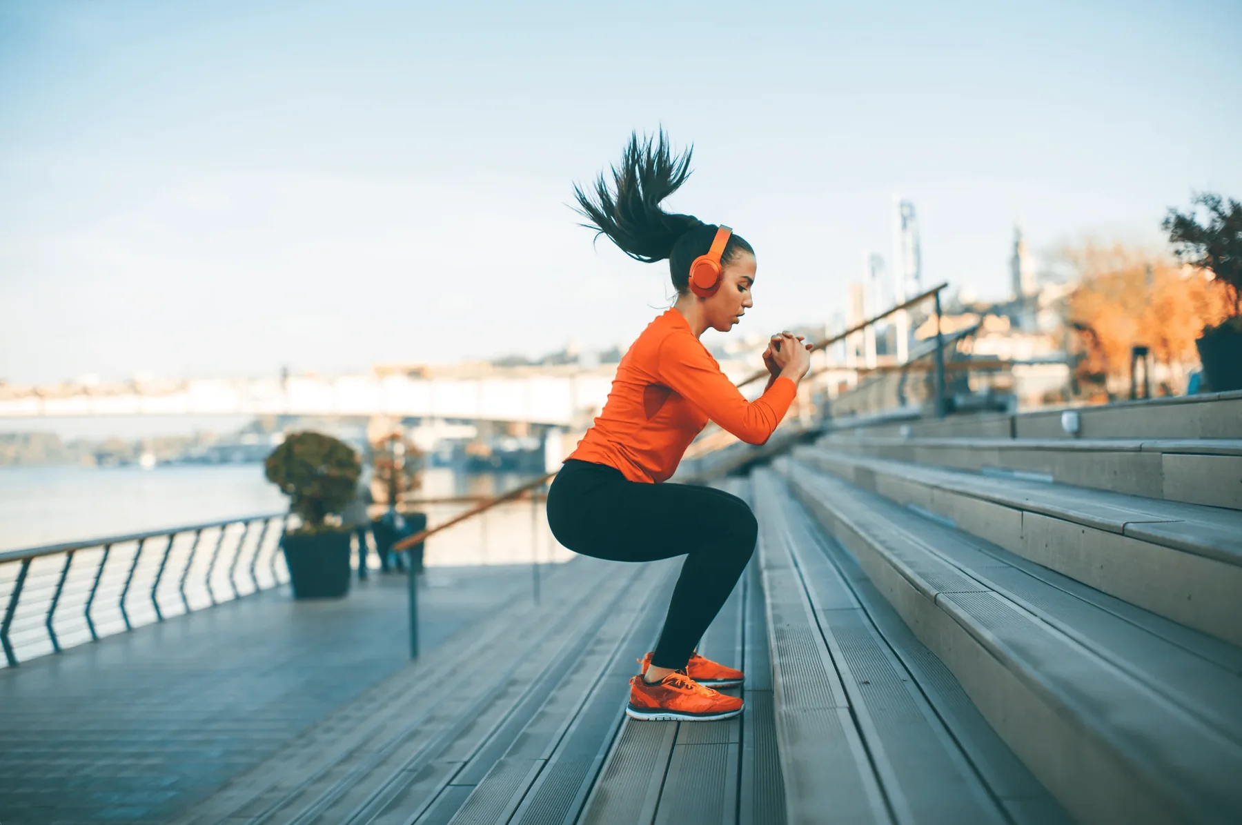 A woman exercising outdoors near a waterfront