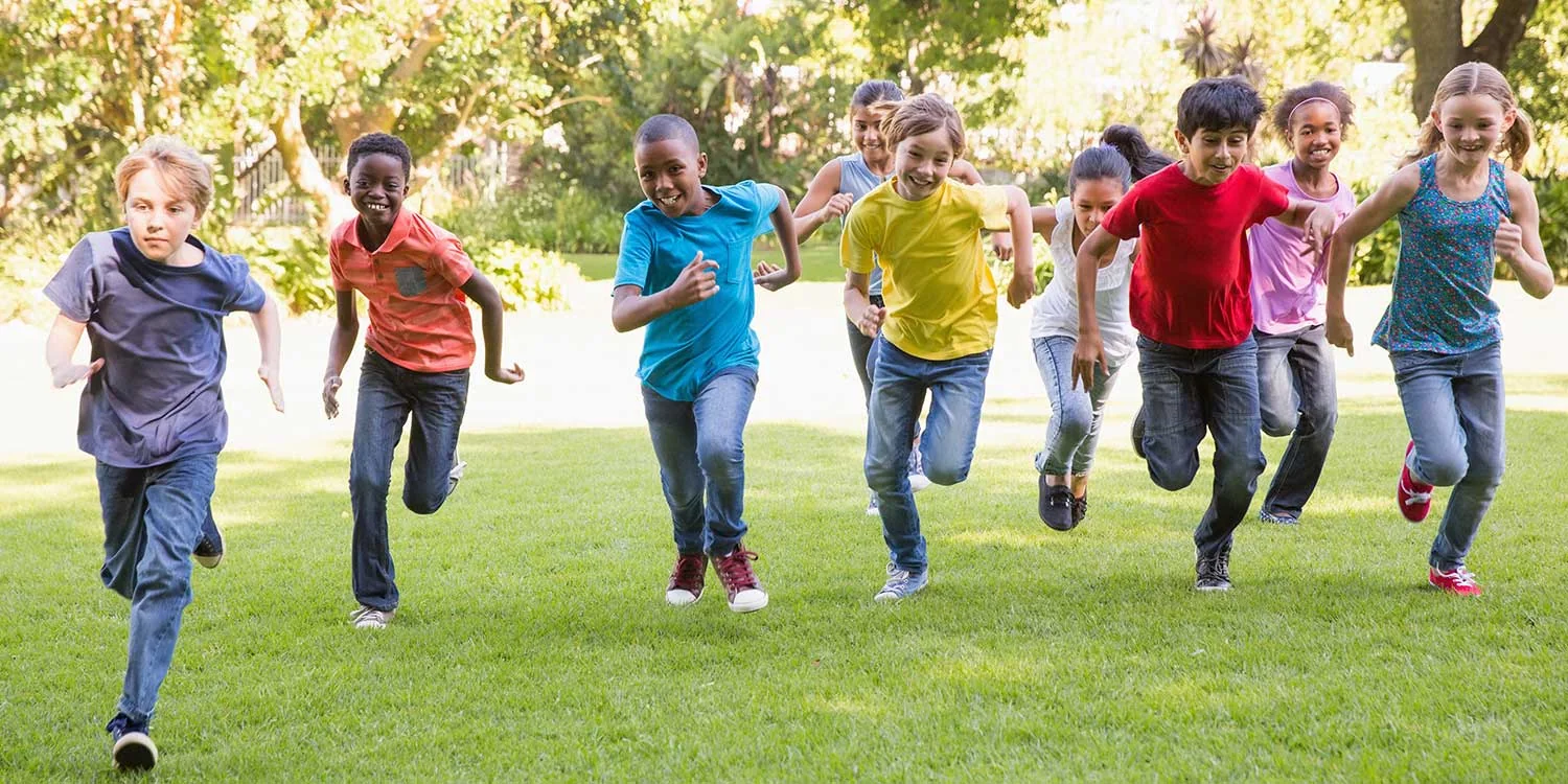 A diverse group of children running together outdoors